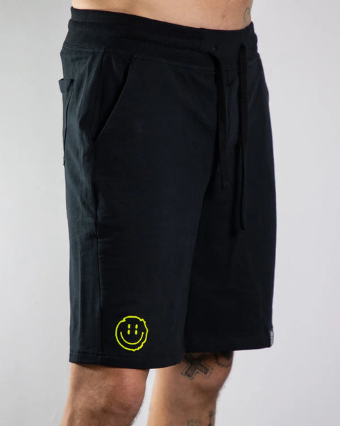 Kurze Raver Hose in schwarz mit Distorted Smile Flockfolien-Aufdruck am Hosenbein, von vorne fotografiert